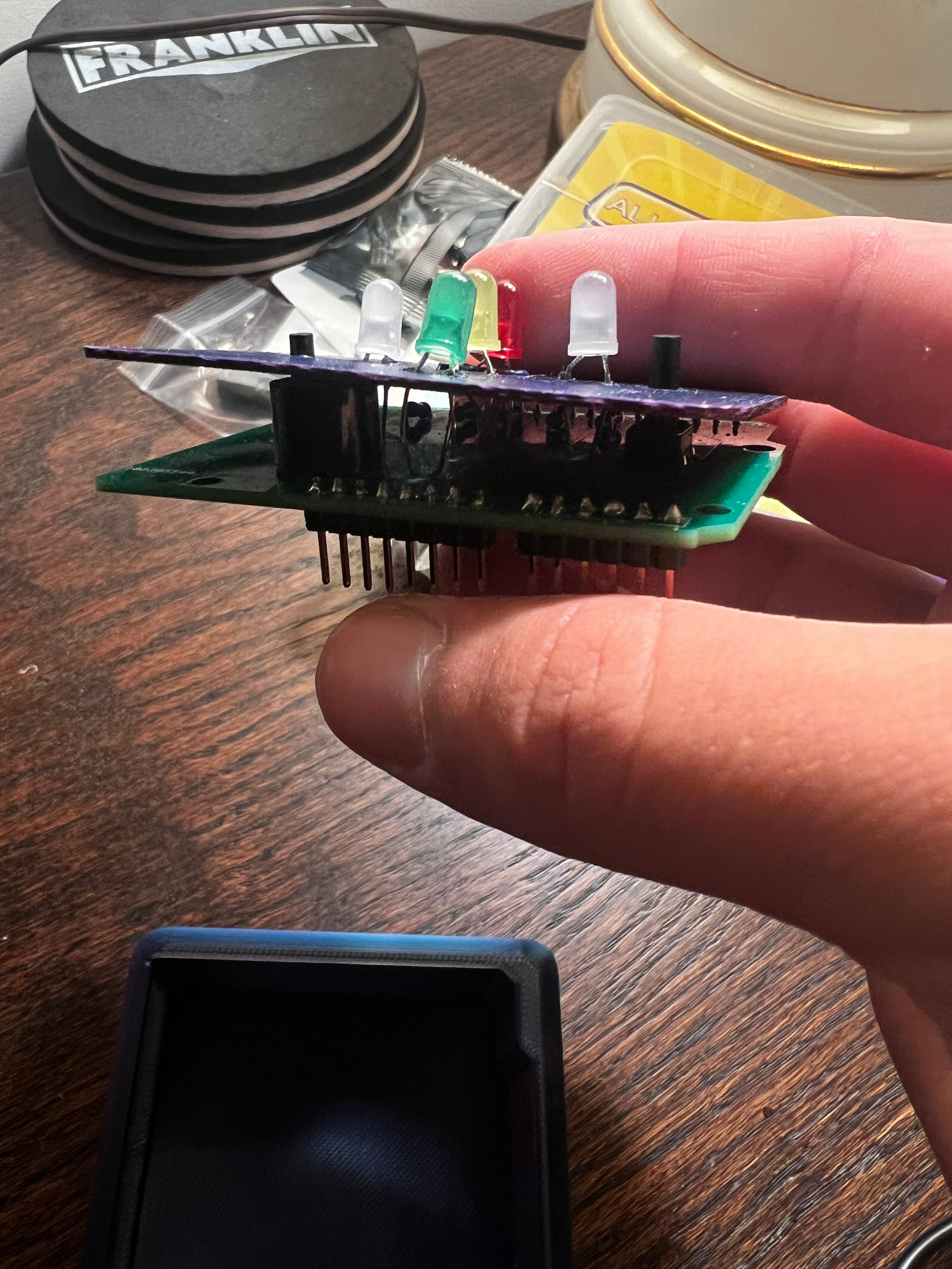 Hand holding assembled PCB with LEDs and components soldered on, purple board visible