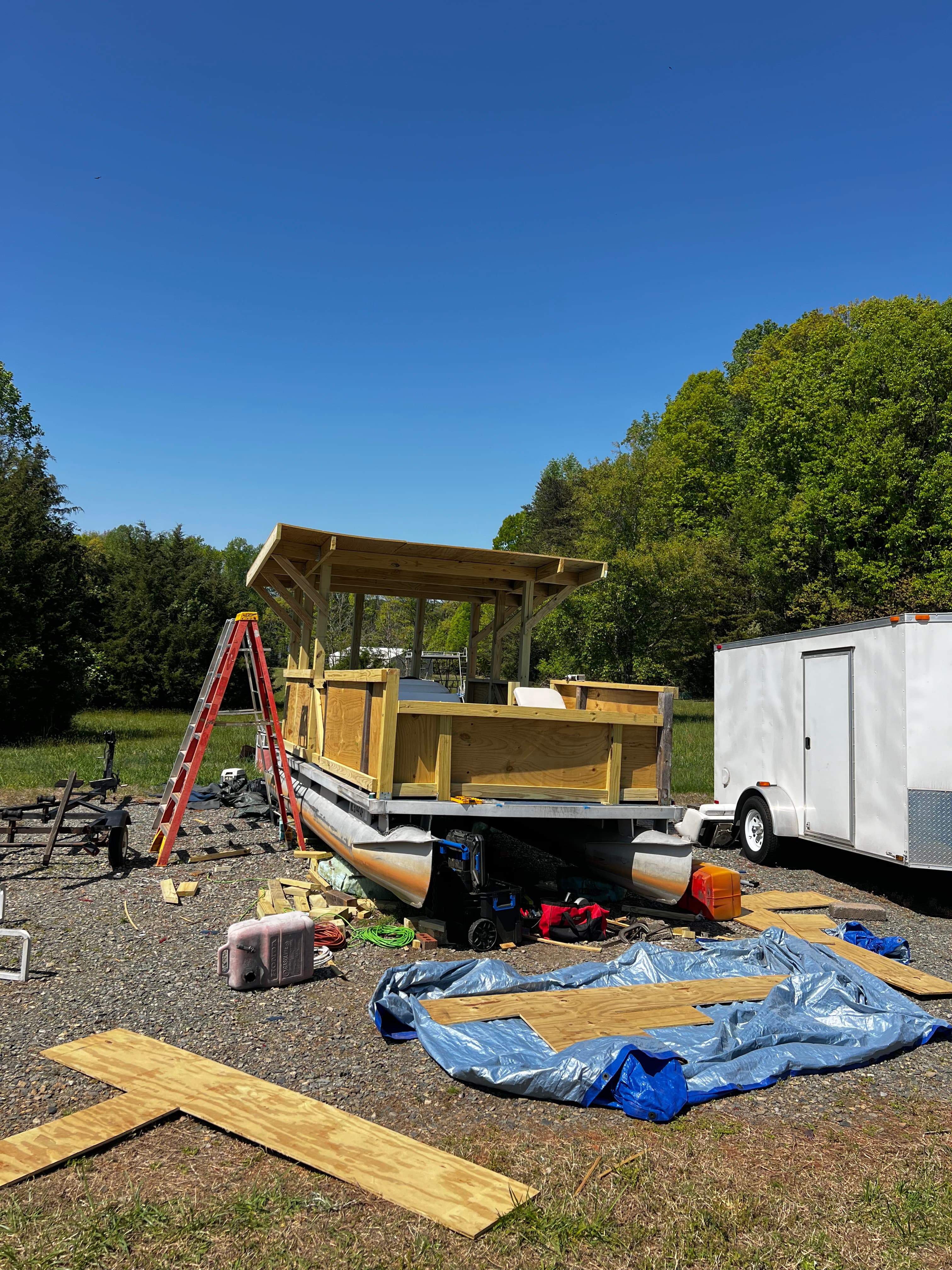 Nearly complete boat in boatyard with ladder leaning against it and blue sky