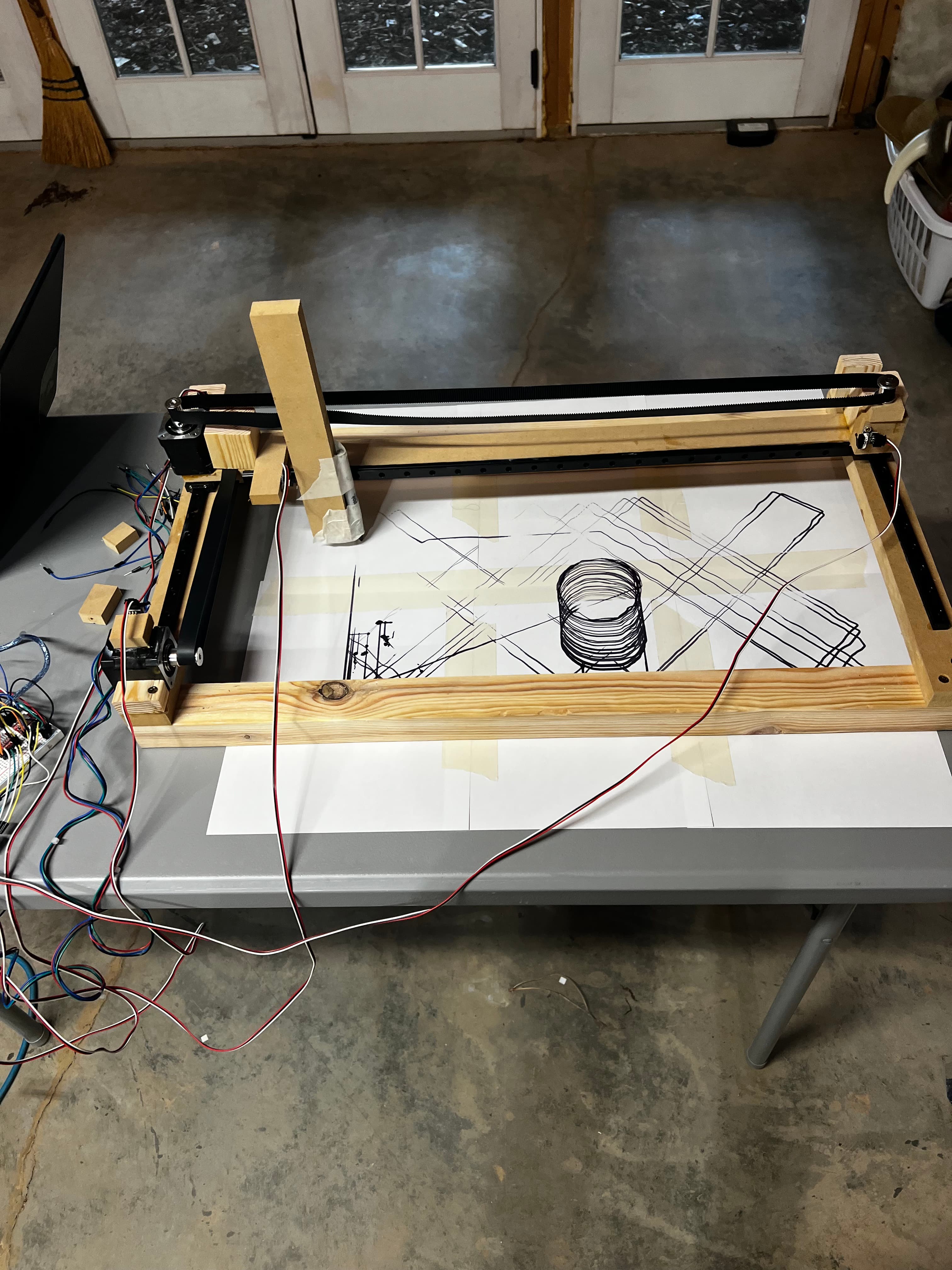 Overhead shot of finished CNC machine on table with circles and lines it produced visible underneath, wiring bundle on left side